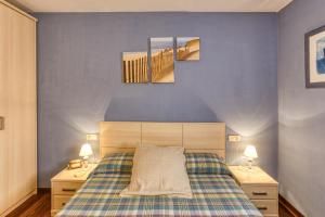 a bedroom with a bed with three paintings on the wall at Cal Tatanet in Sant Pau de Segúries