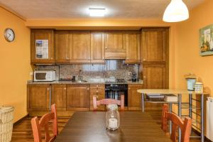 a kitchen with wooden cabinets and a table with chairs at Cal Tatanet in Sant Pau de Segúries