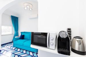 a living room with a blue couch and a microwave at Aurora Luxury Suites Seaview in Positano
