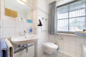 a white bathroom with a sink and a toilet at Fewo Brünnstein - Nr 47 Pool, Sauna in Oberaudorf