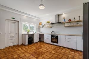 a kitchen with white cabinets and a wooden floor at Palmela Sunset Villa in Quinta do Anjo