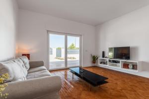a living room with a couch and a tv at Palmela Sunset Villa in Quinta do Anjo