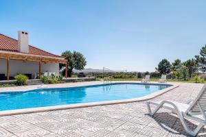 a swimming pool with two chairs and a house at Palmela Sunset Villa in Quinta do Anjo