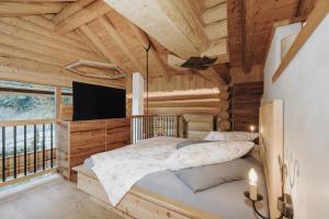 a bedroom in a log cabin with a bed and a tv at Chalet Zwoasom in Grossarl