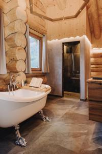 a bathroom with a white tub and a wooden wall at Chalet Zwoasom in Grossarl +27 photos