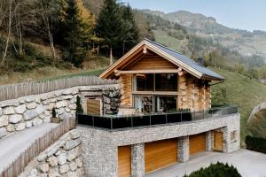 a log house with a stone wall at Chalet Zwoasom in Grossarl