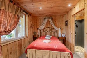 a bedroom with a red bed in a wooden room at Chalet du Pradel in Les Estables