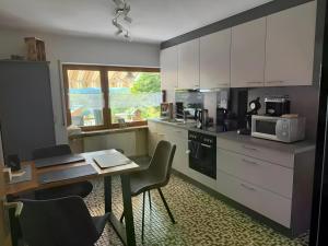 a kitchen with white cabinets and a table with chairs at Komfort trifft Natur in Albbruck