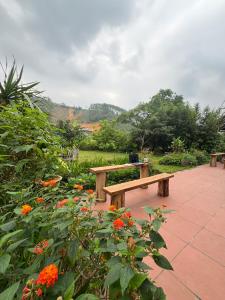 a wooden bench sitting in a garden with flowers at ThongDong Homestay in Hữu Lũng