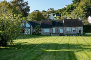 a house with a large yard with grass at Maison Chevoir pieds dans l'eau in Ploubazlanec