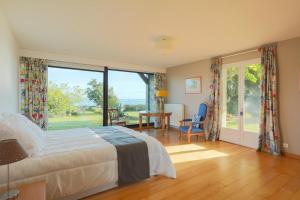 a bedroom with a bed and a large window at Maison Chevoir pieds dans l'eau in Ploubazlanec
