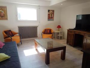 a living room with a couch and a table and a television at Maison D'hôtes en Drôme Provençale in Vinsobres