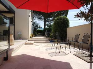 a patio with chairs and a red umbrella at Maison D'hôtes en Drôme Provençale in Vinsobres