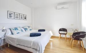 a white bedroom with a bed and two chairs at Llum in Manacor +22 photos