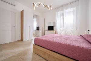 a bedroom with a pink bed in a white room at Casa La Viola - Follonica in Follonica