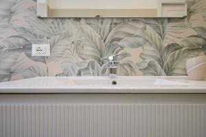 a bathroom sink with a leafy wallpaper on the wall at Casa La Viola - Follonica in Follonica