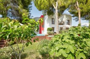 a white house with a red door and trees at Villa Retreats in Santa Eularia des Riu