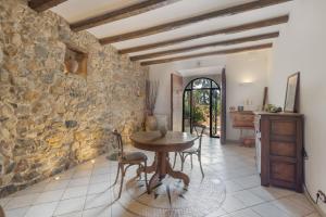 a dining room with a table and a stone wall at Mas Juli in Pineda de Mar