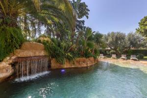 a swimming pool with a waterfall in a yard at Mas Juli in Pineda de Mar