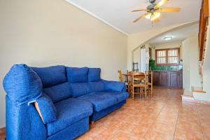a living room with a blue couch and a kitchen at Casa Manolo in Torredembarra