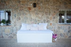 a white bed in a room with a stone wall at Can Ferrer in Alcudia