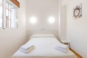 a white room with a bed with towels on it at Entreplayas Benidorm in Benidorm