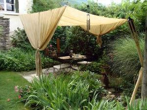an umbrella in a garden with a table and chairs at Gite Les Trois Collines in Cuisiat