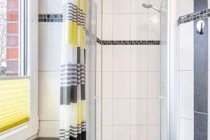 a bathroom with a shower with a yellow and black shower curtain at Ferienwohnung Hilbers in Horumersiel +16 photos