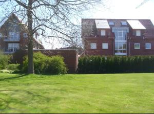 a house in a yard with a green lawn at Ferienwohnung Hilbers in Horumersiel