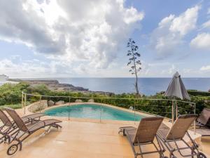 a swimming pool with chairs and the ocean in the background at Villa Rocío in Binibeca
