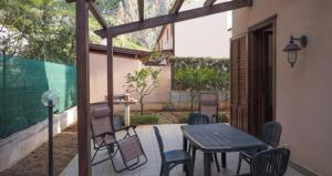 a patio with a wooden table and chairs at Villetta Vittoria in Macari