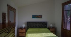 a bedroom with a green bed and a window at Villetta Vittoria in Macari