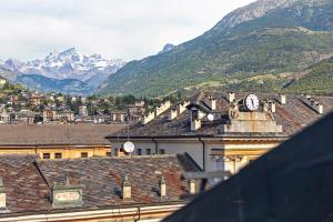a view of a town with mountains and a clock at Mema Holiday Home in Aosta