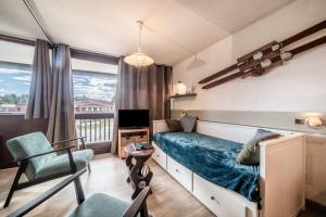 a bedroom with a bed and a chair and a television at Les Mouflons in Taninges