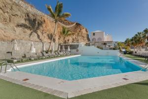 a pool at a resort with chairs and palm trees at Casa Orballo in Mogán
