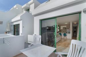 a white house with glass doors and white chairs at Casa Orballo in Mogán