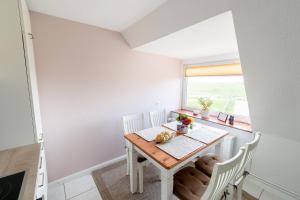 a dining room with a table and chairs and a window at Haus Süderkamp in Langeneß