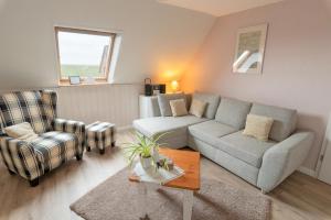 a living room with a couch and two chairs at Haus Süderkamp in Langeneß +2 photos