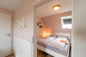 a small bedroom with a bed and a window at Haus Süderkamp in Langeneß