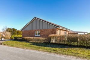 a brick house with a fence next to a street at Ferienhaus Waterkant mit Hund in Klanxbüll
