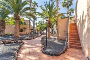a pathway with palm trees and a street light at Casa Alvates in Corralejo