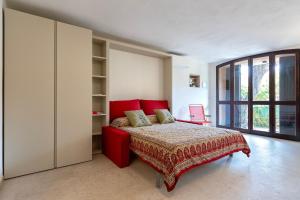 a bedroom with a red bed and a large window at Villa Grecale in Stintino