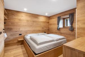 a bedroom with a bed in a wooden wall at Agriturismo Montespluga in Madesimo