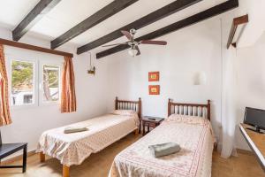 two beds in a room with a ceiling fan at Cala Serena Beach 5 in Felanitx