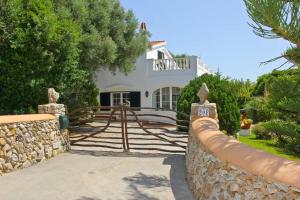 a large white house with a fence and a stone wall at Las Tórtolas in Alaior