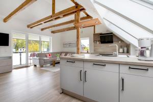a kitchen with white cabinets and a living room at Ferienhaus Schleibengel in Maasholm