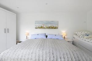 a white bedroom with a bed and a painting on the wall at Ferienhaus Schleibengel in Maasholm +26 photos