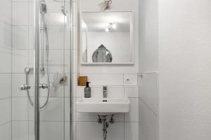 a white bathroom with a sink and a shower at Ferienwohnung Im Laubgarten in Öhningen +16 photos