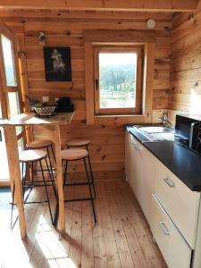 a kitchen in a log cabin with a table and stools at Au chant des oiseaux - rouge gorge in Varen