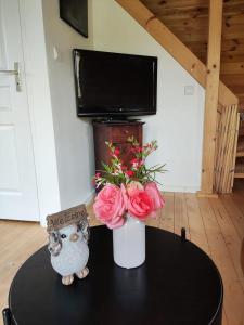 a table with a vase of flowers and a tv at Au chant des oiseaux - rouge gorge in Varen